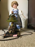 Full view of the doll standing behind the frog prince lamp showing both items in the lot