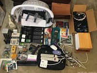 Photo showing large assortment including 3 USB keyboards in a white hamper, multiple calculators, power strips, various cables, laptop bag, computer peripherals and office supplies.