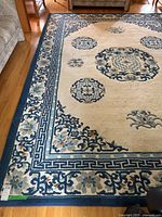 Overall view of rug on hardwood floor, showing full medallion and border pattern.