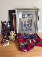 Overview photo showing several items on table including stone figures, mask, framed art, candle holders, and fabric pieces
