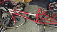 Side view of red and white Parex bicycle showing frame, front tire, pedals and crankset.