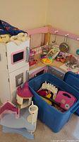 Corner view of white and pink mock kitchen playset with plastic pots, pans, utensils, plastic food items and accessories on countertop, included with the lot.