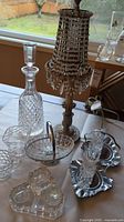 Crystal glassware lot on table including decanter, glass beaded lamp, candy dishes, and glasses.