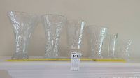 Group photo showing all six crystal vases lined up from tallest to shortest next to a yellow measuring tape for scale.
