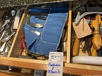 Drawer with assorted kitchen utensils including wooden handled tools and a blue fabric knife roll