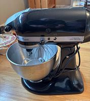 Black KitchenAid Classic stand mixer with bowl and attachments on wooden surface