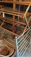 Wooden drying rack with multiple slats and natural wood finish showing discoloration. Wicker baskets partially visible below.