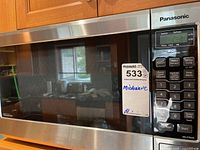 Front view of Panasonic NN-ST663S inverter microwave showing stainless steel and black finish with control panel on the right side and sticker showing lot number and label 'Microwave'.