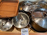 Overview of pots and pans in drawer showing various lids and wire frying baskets