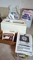 Photo showing Husqvarna 2000 sewing machine in off-white color with operating manual and sewing machine cover instructions booklet on top, lots of sewing materials around including polyester fiber fill bag and a crochet book.