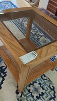 Full view of the rectangular wooden side table with glass inset top and cane bottom shelf showing the structure and design.