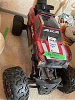 Front and top view of the red and black 4x4 remote control toy car with visible large tires and body decals