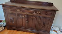 Front view of the vintage wood side board showing carved details on drawer and doors.