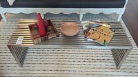 Front view of stainless steel slatted coffee table with decor items and books