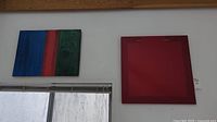 Wall-mounted original paintings: one striped and one solid red, both approximately 24x24 inches.