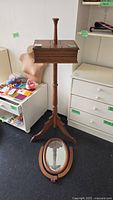 Full view of wooden vanity stand with storage box on top, missing attached mirror which rests separately on the floor.
