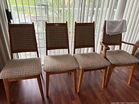 Four wooden dining chairs with fabric seats and backs in beige plaid pattern
