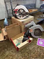 Image showing the Sears Craftsman 30 electric circular saw on top of a box, a Black & Decker electric circular saw, a Snap-on soldering tool inside its box, and an electric handheld sander nearby.