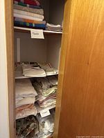 Shelves with labeled stacks of towels and bed linens.