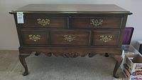 Front view of vintage cedar love chest showing false drawers with brass handles and carved legs.