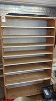 Front view of the tall wooden shelves showing the eight storage levels and the base shoe mat.