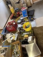 Overall view of collection showing multiple boxes and containers with tools, cords, and yard equipment including weed eater and hedge trimmer.