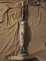 Full view of Bissell steam mop showing handle, control button, and triangular cleaning head with microfiber pad.