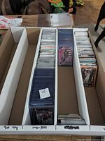 Box divided into four compartments with hundreds of sleeved sports trading cards