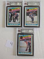 Photo of the front sides of 3 graded Wayne Gretzky hockey cards from 1984-85 O-Pee-Chee set showing Scoring Leader, Goal Leader, and Assist Leader versions.