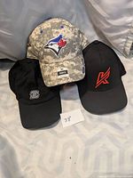 Front view of the three sports hats: digital camo Blue Jays, black Knapper, black Sherwood.