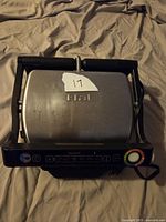 Front and top view of Tfal OptiGrill Smart indoor electric grill showing black and stainless steel design with control panel and Tfal logo.