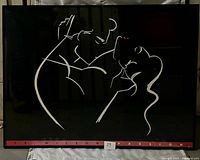 Photo of the framed 'Passion' print by Ty Wilson, showing the black background and white line drawing of a couple embracing. The bottom border with 'Ty Wilson Passion' text is visible.