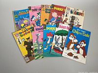 Ten vintage comic books including Beetle Bailey, Blondie, Yosemite Sam, Porky Pig, Bugs Bunny, and Chip n' Dale arranged fanned out on a white surface. Covers show classic cartoon art.