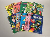 Ten assorted vintage comic books with colorful covers laid out, featuring characters such as Richie Rich, Moby Duck, Tweety and Sylvester, Pebbles and Bamm-Bamm, Bugs Bunny, Chip n Dale, Dastardly and Muttley, and Donald Duck.