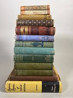 Stack of 13 hardcover books showing varied spine designs and colors.