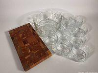 Photo showing large glass bowl with nine smaller glass bowls grouped beside a wooden cutting board, illustrating the entire set.