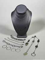 Full set of vintage 925 silver jewelry including necklaces held on a black display bust, various bracelets, hoop earrings, and one decorative bead bracelet arranged in front.