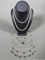 Overview of two necklaces on bust and three bracelets laid out