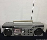 Full front view of the vintage Eaton Viking SPC5496 cassette player on black fabric background, showing built-in speakers, cassette compartment, and antenna extended.