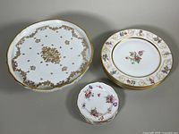 Set of bone china dishes arranged with pedestal cake plate, stacked Limoges plates, and small Spode dessert plates