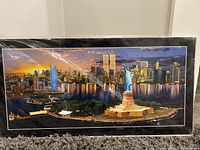 Framed aerial photograph showing Twin Towers, Statue of Liberty, and city skyline at sunset