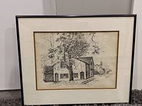 Framed ink drawing of a house and trees, signed by Anne Renmer, showing overall composition and framing.