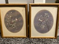 Two framed vintage bird art prints, set side by side, showing details of birds on flowering branches in oval mats within wooden frames.