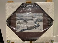 Full view of framed artwork showing winter snow-covered rural setting with river and houses.