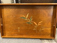 Full view of the wooden tray showing bamboo leaf design and carved handles
