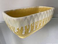 Close-up side angle showing textured cream glaze with yellow drip effect and glossy yellow interior.