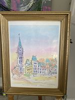 Photo showing the full framed print of the Parliament Building in Ottawa by Diane Arnold with gold-tone frame and pastel sky background.