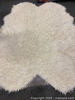 Top view of the white shag rug showing its shaggy texture and wavy scalloped edge shape.