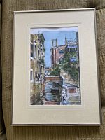 Frontal photo of the matted and framed watercolour painting showing full scene of Venetian canal with bridge, buildings, and gondola.