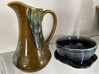 Photo of large brown and green drip glazed ceramic pitcher with handle and spout